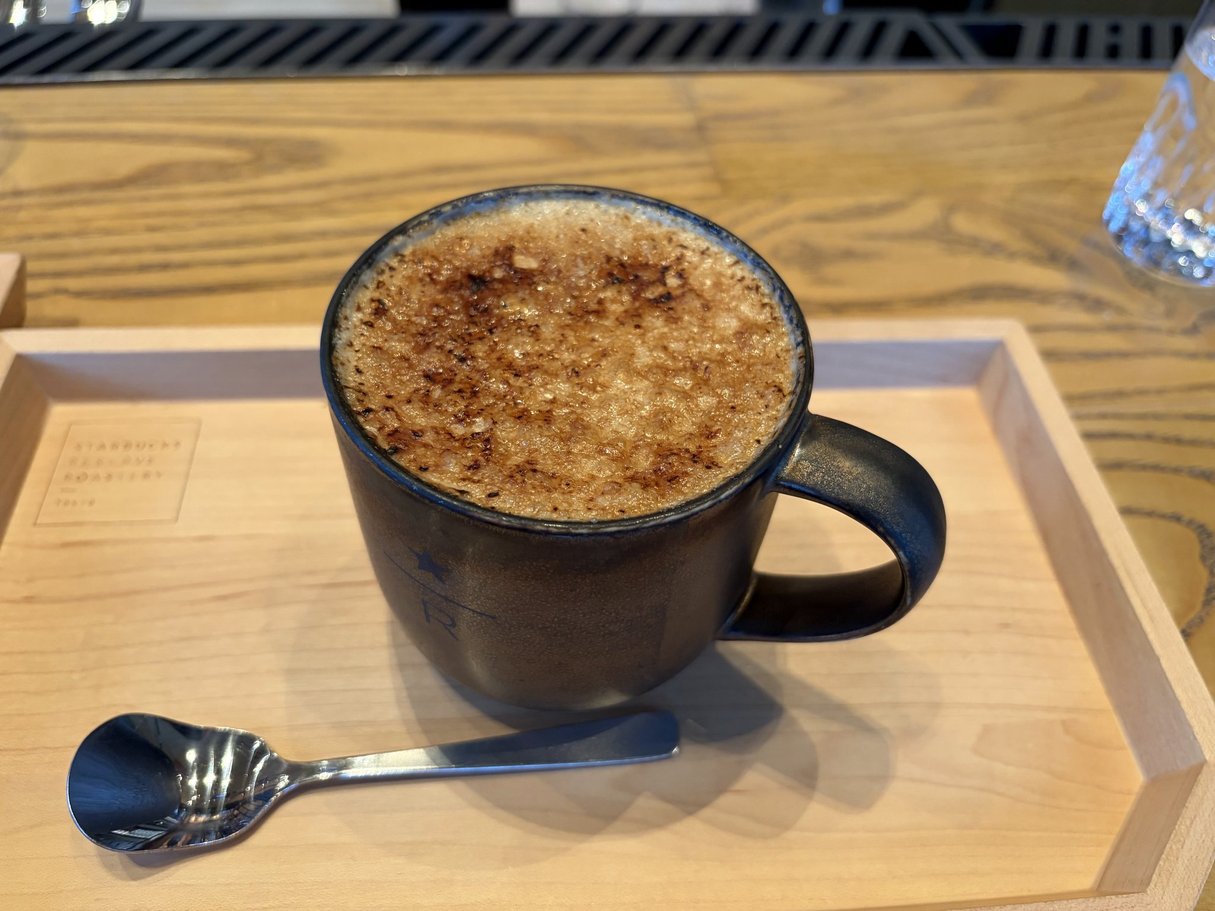 木のトレーに置かれた、黒いマグカップに入ったコーヒー